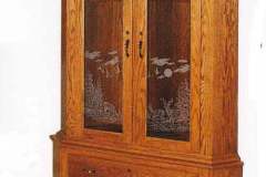 Amish made corner gun cabinet crafted out of solid oak.  This gun cabinet features two arched glass upper doors and two full extension drawers in the lower cabinet.