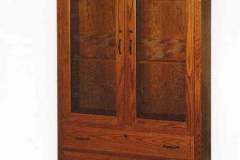 Amish crafted one piece two door gun cabinet with arched glass upper doors, two full extension lower drawers, and classic dentil molding.  Shown in red oak but can be crafted in hickory, walnut, maple, or quarter sawn white oak.