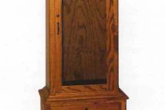 Amish crafted solid oak single door gun cabinet with two full extension drawers in the lower cabinet.  Upper cabinet features a soft arch and dentil molding.